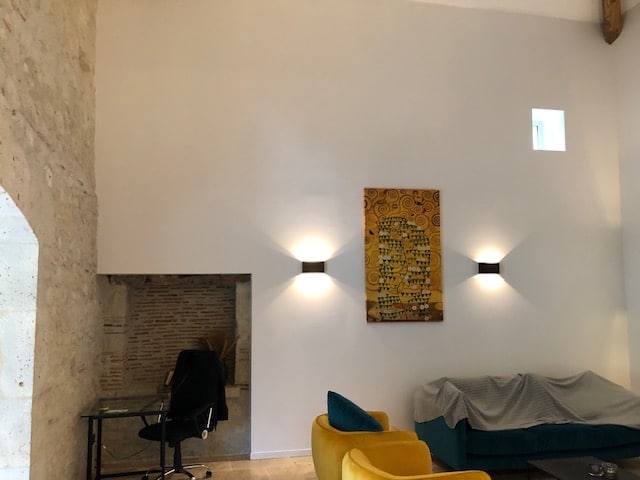 Décoration Intérieur Moderne : Salon avec Appliques et Art Salon moderne avec fauteuil jaune, appliques murales, tableau de Klimt et canapé sur mur blanc épuré.